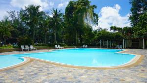 a large swimming pool with chairs and trees at VIP Condochain Rayong 410 in Ban Phe