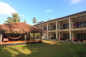 a large building with a thatch roof and a yard at JJ's Hostel Mirissa in Mirissa