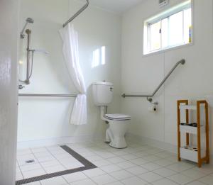 a white bathroom with a toilet and a window at Pelican Waters Holiday Park in Port Fairy