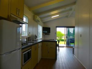 a kitchen with yellow cabinets and a large window at Pelican Waters Holiday Park in Port Fairy