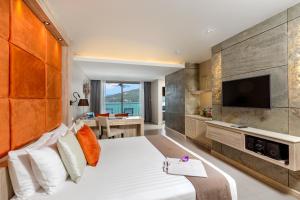 a hotel room with a large bed and a television at Cape Sienna Phuket Gourmet Hotel & Villas - SHA Extra Plus in Kamala Beach