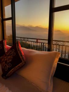 a bed with pillows in front of a window with a view at Superview Lodge Sarangkot in Pokhara