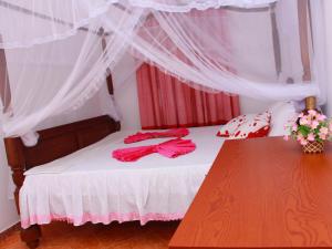 Schlafzimmer mit einem Bett mit roter Kleidung in der Unterkunft Moon Glow Guest in Mirissa