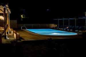 uma piscina à noite com um deque e cadeiras em Anemoessa Luxury Villas em Fanari