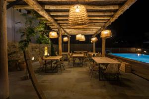 a patio with tables and chairs next to a pool at Anemoessa Luxury Villas in Fanari