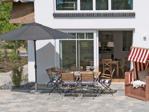 a table and chairs with an umbrella on a patio at Reetperle Lobbe - Ferienhaus mit Sauna (F 650) in Lobbe