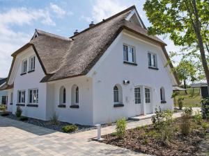 a white house with a gray roof at Reetperle Lobbe - Ferienhaus mit Sauna (F 650) in Lobbe