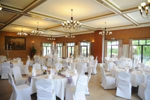 a room with white tables and chairs and chandeliers at Waldhotel Rheinbach in Rheinbach