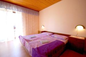 um quarto com uma cama roxa e uma janela em Apartments Begic em Malinska