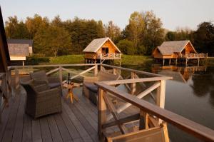 une terrasse avec des chaises et une maison sur l'eau dans l'établissement Aqualodge Hôtel Insolite, à Ermeton-sur-Biert