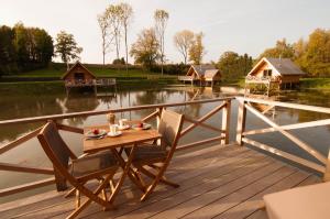 a table and chairs on a wooden deck next to a body of water at Aqualodge Hôtel Insolite in Ermeton-sur-Biert