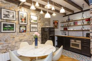 une cuisine avec une table et des chaises ainsi qu'un mur en pierre dans l'établissement Ateliers de Montmartre ADM, à Paris