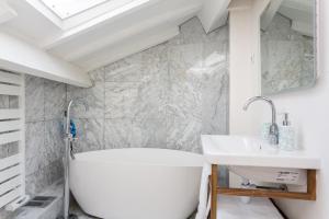 a white bath tub sitting under a window in a bathroom at Ateliers de Montmartre ADM in Paris
