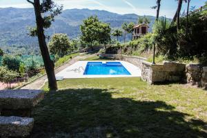 Un patio trasero con piscina y una casa. en Encostas da Torre, en Terras de Bouro