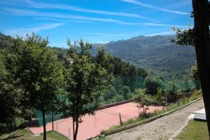 a tennis court with trees and mountains in the background at Encostas da Torre in Terras de Bouro