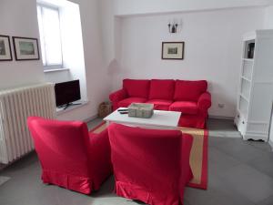 ArizzanoにあるCasa Amabile con Piscinaのリビングルーム(赤いソファ、椅子付)