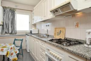 a kitchen with white cabinets and a stove top oven at Mar De Cunit in Cunit