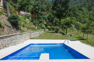 a swimming pool in a yard with a stone wall at Encostas da Torre in Terras de Bouro
