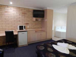 a hotel room with a bed and a kitchen with a microwave at Cotswold Motor Inn in Toowoomba