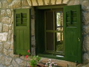 a window with green shutters on a stone building with flowers at Apartments Cvita in Veli Lošinj