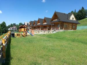 a large log cabin with a fence in a field at Domki Prokop in Ciche