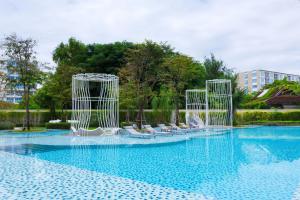 uma piscina com cadeiras brancas na água em Summer HuaHin Condominium em Hua Hin