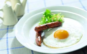 a plate of breakfast food with sausage and an egg at Dobr Zdravich in Ufa