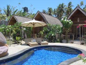 a swimming pool with an umbrella and a house at Djamezz Lumbung in Gili Air