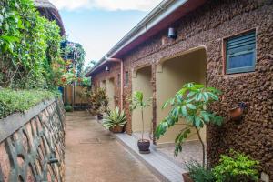 an alley with potted plants next to a brick building at Hotel Gorilla's Nest Entebbe in Kitende