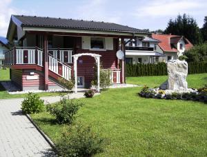 ein Haus mit einer Veranda und einem Rasenplatz in der Unterkunft Romantica in Drobollach am Faakersee