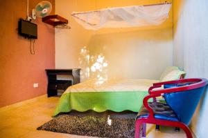 Hotel Gorilla's Nest Entebbe في Kitende: غرفة نوم فيها سرير وكرسي