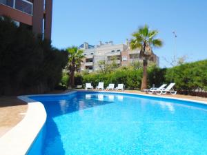 a large blue swimming pool with chairs and a building at Beautiful Apartment Litoralmar in Portimão
