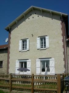 a brick building with a fence and a umbrella at Gite de la ferme du couvent in Boran-sur-Oise
