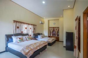 a bedroom with two beds and a tv in it at Maharani Homestay in Banyuwangi