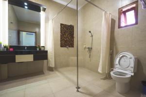 a bathroom with a shower and a toilet and a sink at Maharani Homestay in Banyuwangi