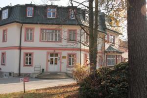 a large white house with a black roof at Tatranka a Horalka in Tatranská Lomnica