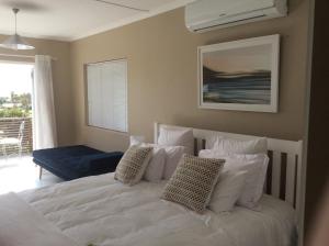 a bedroom with a white bed with pillows at Kommetjie Heaven in Kommetjie