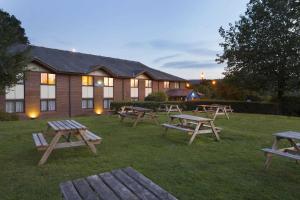 un grupo de mesas de picnic frente a un edificio en Days Inn Taunton, en Taunton