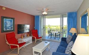 基韋斯特的住宿－Sunrise Suites Antigua Suite #312，客厅配有蓝色的沙发和红色的椅子