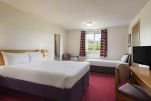 a hotel room with a large bed and a tv at Days Inn Tewkesbury in Strensham