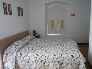 a bedroom with a bed with a white bedspread and a window at Casa do Arco da Praça in Elvas