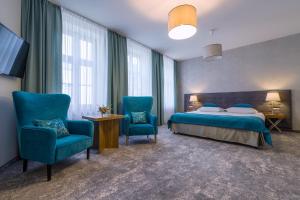 a bedroom with a bed and two blue chairs at Hotel Patio Old Town in Wrocław