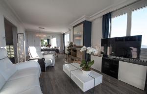 ein Wohnzimmer mit weißen Möbeln und einem Flachbild-TV in der Unterkunft Chambres d'hôtes Villa Volcano in Durtol