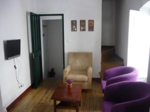 a living room with a chair and two purple chairs at Casa do Arco da Praça in Elvas