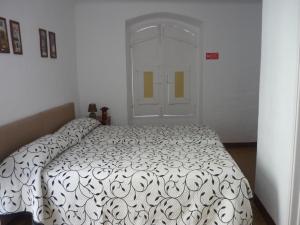 a bedroom with a bed with a black and white comforter at Casa do Arco da Praça in Elvas