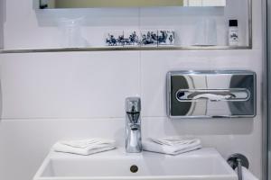 a white sink sitting under a mirror in a bathroom at Hotel Die Port van Cleve in Amsterdam