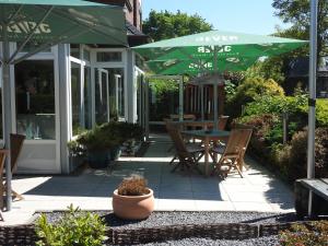 a patio with a table and a green umbrella at ankerplatz-Hotel garni in Wilhelmshaven