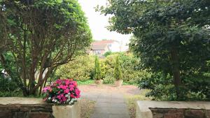 a garden with pink flowers and trees and a house at Sarum Apart-Hotel in Saint Helier Jersey