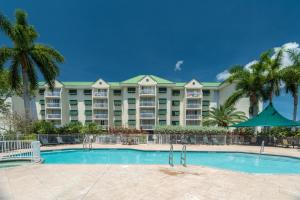 a large apartment building with a swimming pool and palm trees at Sunrise Suites Jamaica Suite #102 in Key West