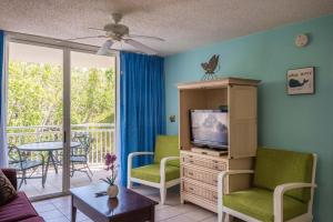 un soggiorno con TV e balcone di Sunrise Suites Jamaica Suite #102 a Key West